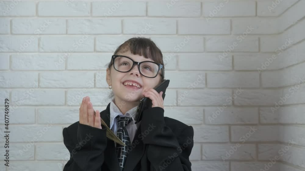 A rich business child. A little girl is talking on the phone and money is falling from above. A rich business child. A little girl is talking on the phone and money is falling from above.