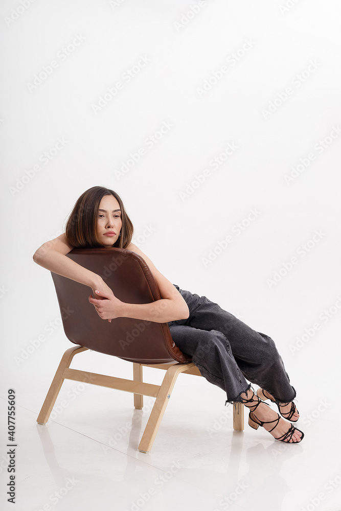 portrait of young attractive asian woman with long brown hair in black clothes, isolated on white studio background. skinny pretty female lying on chair on cyclorama. model tests of beautiful lady portrait of young attractive asian woman with long brown hair in black clothes, isolated on white studio background. skinny pretty female lying on chair on cyclorama. model tests of beautiful lady