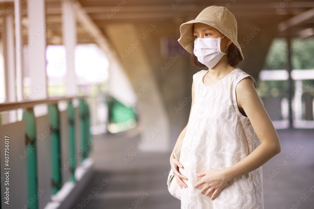 Asian pregnant woman with medical face mask to protect the Covid-19, new normal lifestyle