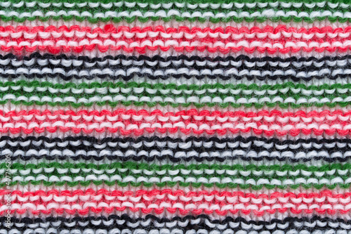 Close-up of hand made knitted stitch wool pattern in red, white, black and green.