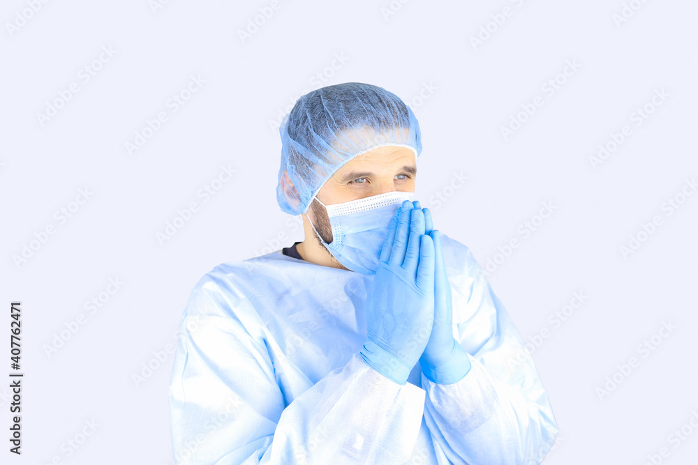 Man in a medical gown, mask and gloves folded his hands in supplication Man in a medical gown, mask and gloves folded his hands in supplication