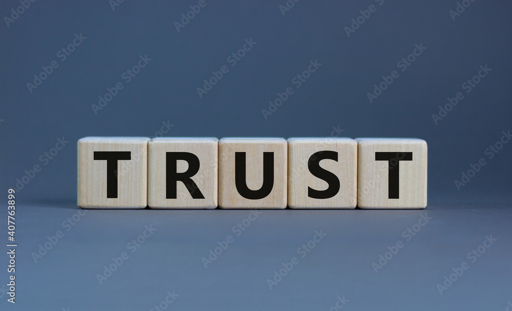 Trust symbol. Concept word 'trust' on wooden cubes on a beautiful grey background. Business and trust concept. Copy space.