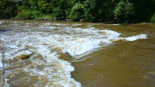 Turbulent gushing river water, vertiginous flow, swirling foamy water waves after heavy rain, turbid water rapids of Mur river, Austria