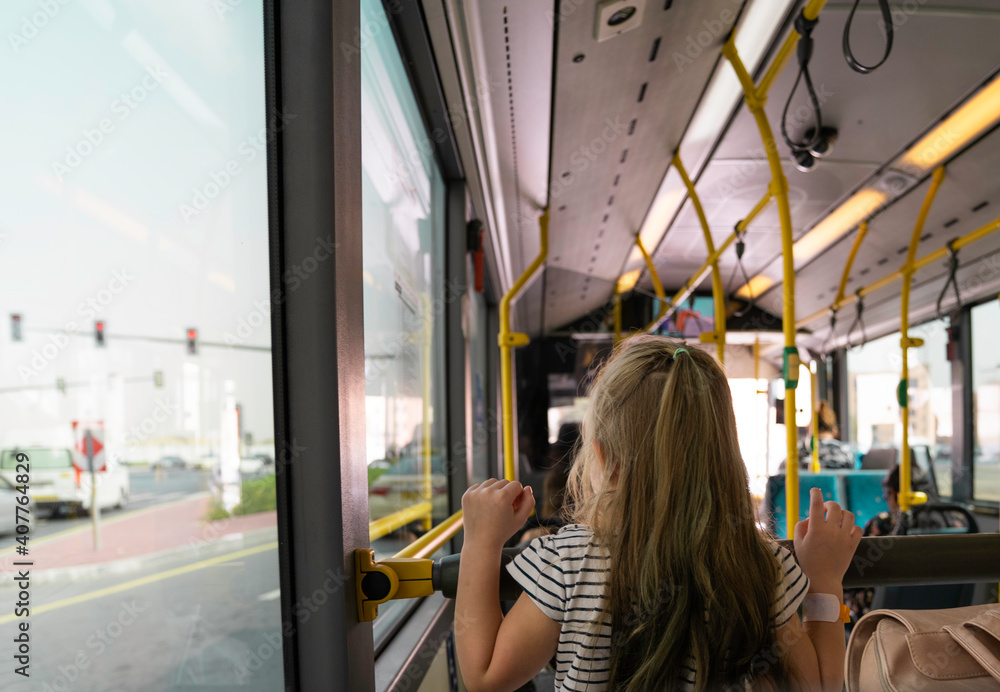 Obraz premium light-haired girl riding a bus, view from the back