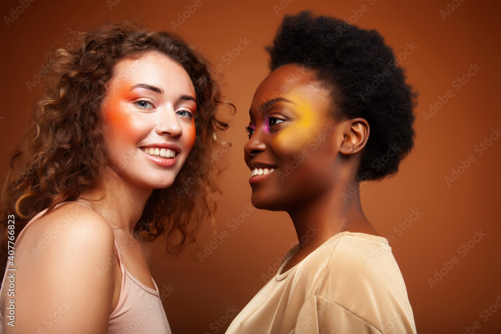 two pretty girls african and caucasian blond posing cheerful together on brown background, ethnicity diverse lifestyle people concept two pretty girls african and caucasian blond posing cheerful together on brown background, ethnicity diverse lifestyle people concept