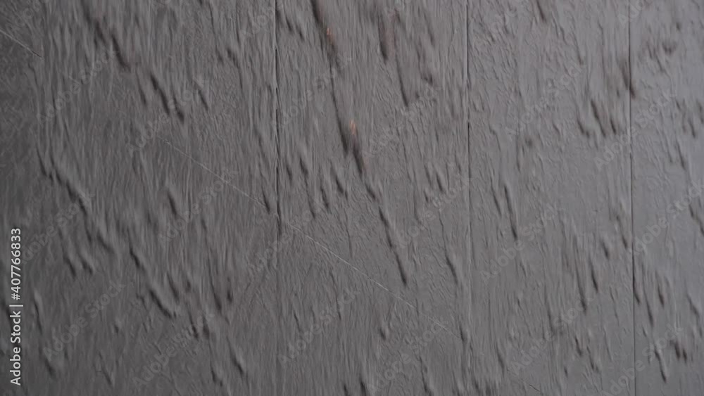 Hard rain in a city. Water flows along black stone wall Hard rain in a city. Water flows along black stone wall