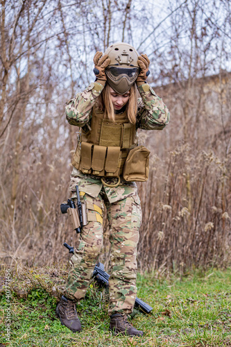 Beautiful girl in military uniform putting on her helmet