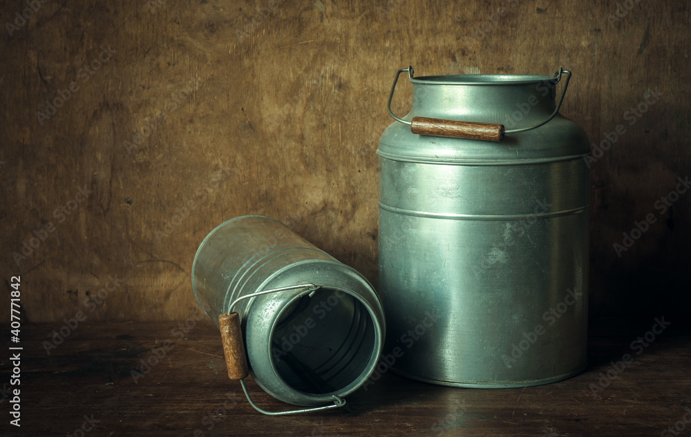 Fototapeta premium Metal cans with wooden handle for milk. On a wooden background in a retro style.