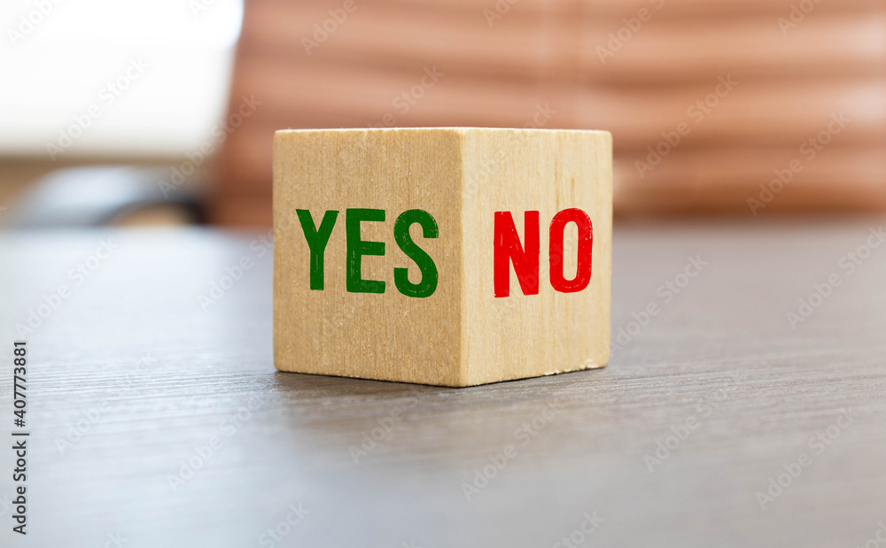 Hand making a choice between two cubes with Yes and No on neutral background Hand making a choice between two cubes with Yes and No on neutral background