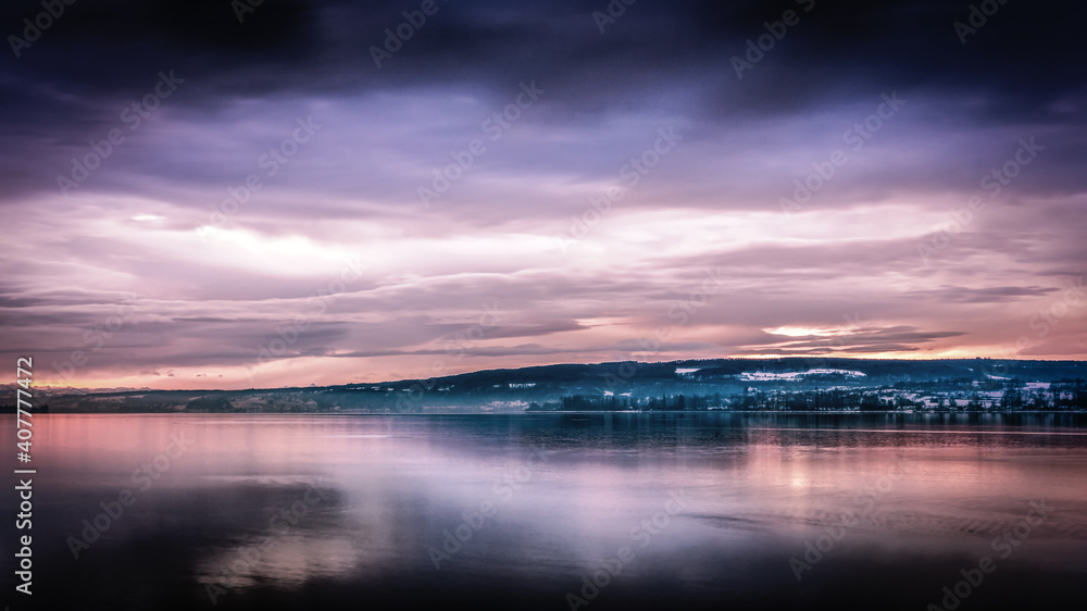 Traumhafter Sonnenaufgang im Winter am schönen Bodensee mit lila Wolken am Himmel 