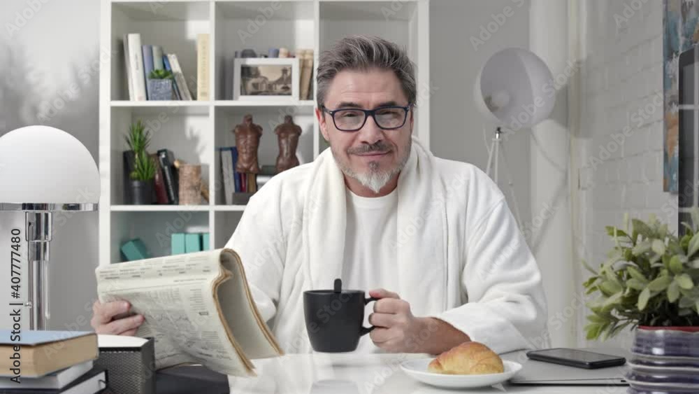 Portrait of older man sitting at desk at home in morning, reading newspaper drinking coffee, smiling. Portrait of older man sitting at desk at home in morning, reading newspaper drinking coffee, smiling.