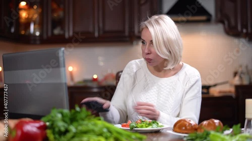 Hurrying young woman eating dinner, surfing Internet on laptop, and talking on the phone. Portrait of modern Caucasian lady combining lunch and business at home. Life balance concept.