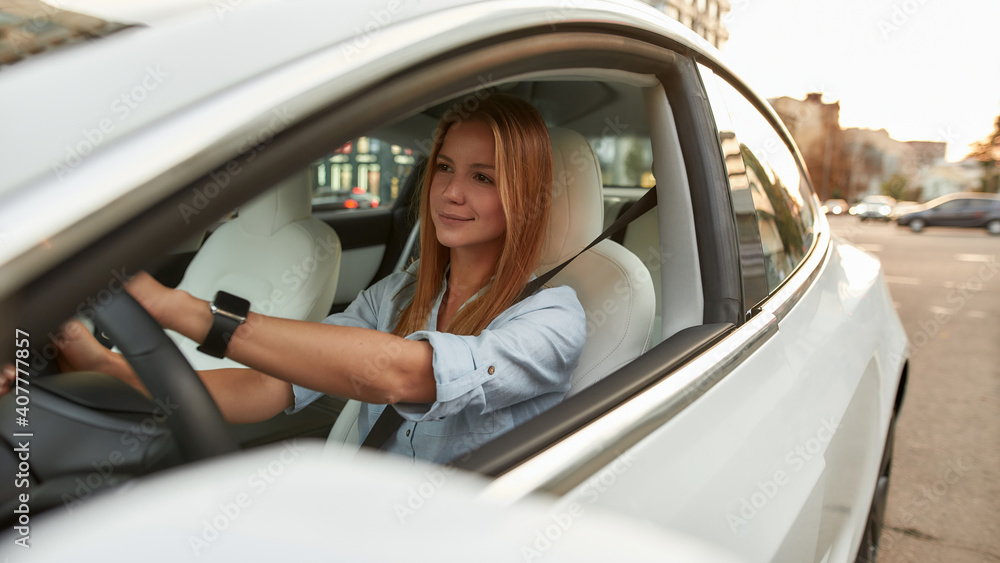 Portrait of cute young caucasian woman driving luxury car