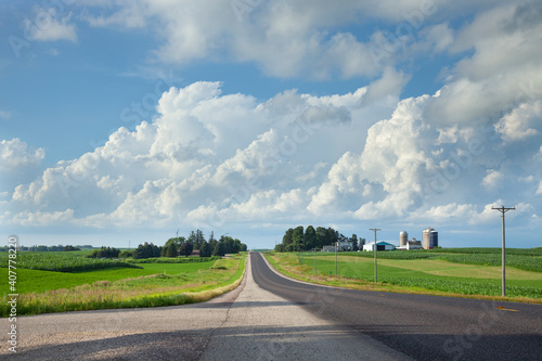 Rural highway in southern Minnesota with fields and a farm beneath dramatic clouds
