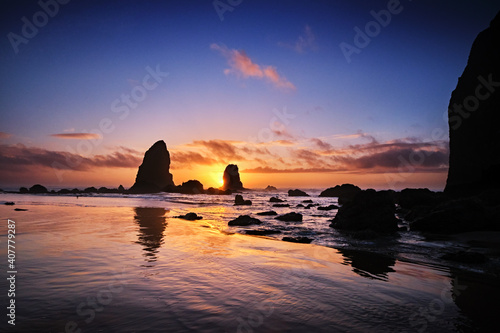 Sun about to set behind The Needles as tide pools around Haystack Rock fill with water as the tide comes in