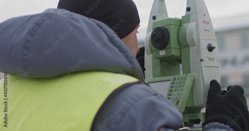 Worker Professional Surveying Engineer in the open space. A professional surveyor takes action with a theodolite using a digital optical device to measure the coordinate Worker Professional Surveying Engineer in the open space. A professional surveyor takes action with a theodolite using a digital optical device to measure the coordinate