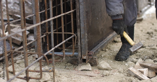 Engineers work with metal constructions while building a house. The worker fixes the form for pouring concrete, aligns metal boards. Filling the foundation of the building