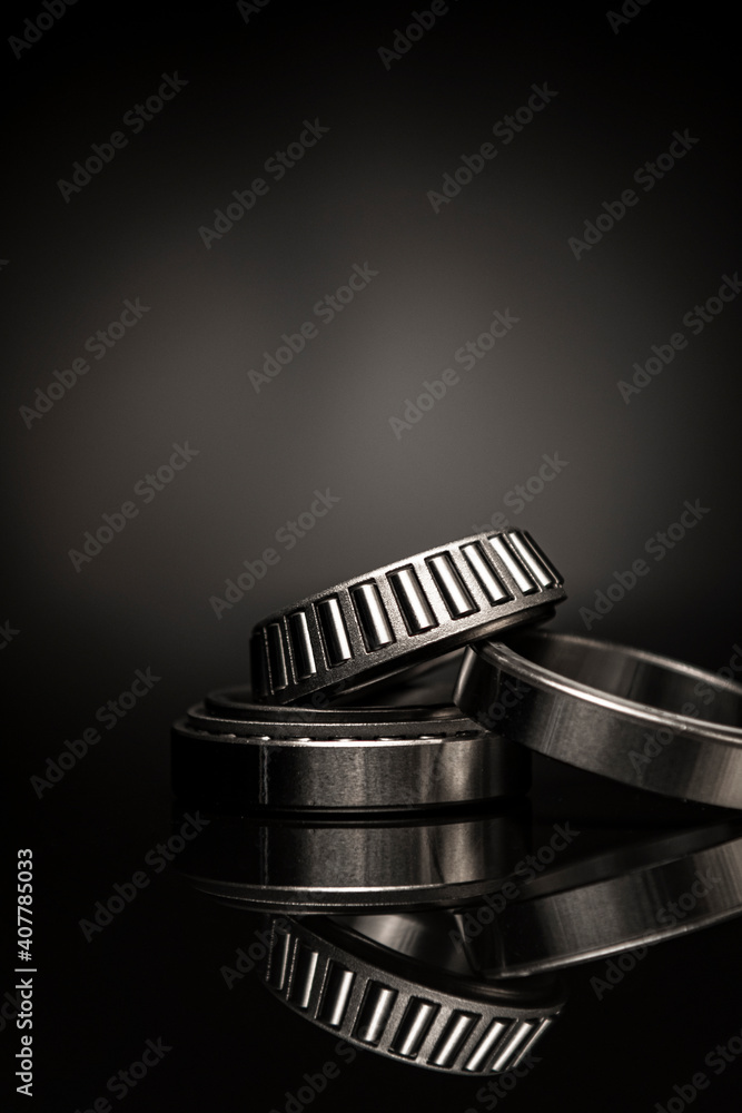 Car bearings, auto parts, steel automotive bearings, placed on black reflective surface, on black background. Car bearings, auto parts, steel automotive bearings, placed on black reflective surface, on black background.
