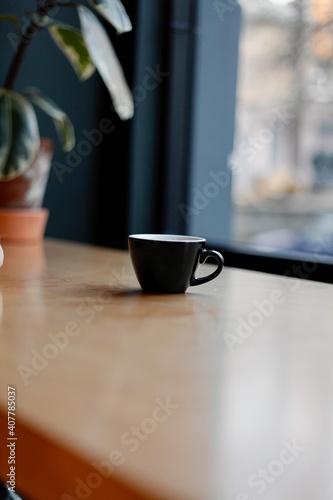 black cup stands on the table against the background of the window