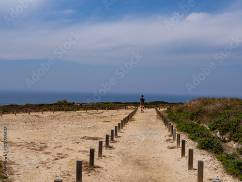 Person wlking alone in a sand path to the beach cliff in costa vicentina, alentejo, portugal
