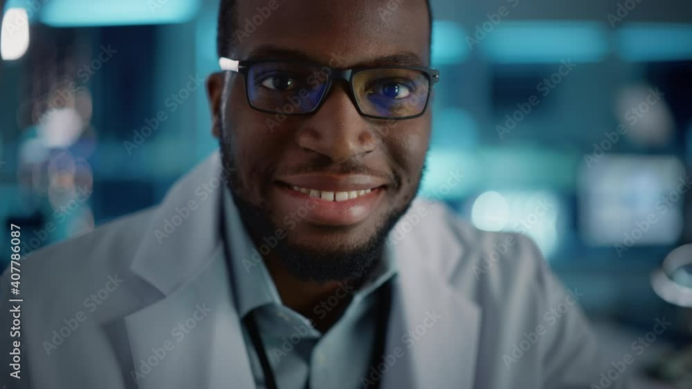 Handsome Black Man Wearing Glasses Smiling Charmingly Looking at Camera. Young Intelligent Male Engineer or Scientist Working in Laboratory. Technological Bokeh Blue Background. Close-up Shot Handsome Black Man Wearing Glasses Smiling Charmingly Looking at Camera. Young Intelligent Male Engineer or Scientist Working in Laboratory. Technological Bokeh Blue Background. Close-up Shot