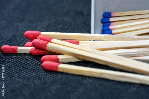 Closeup of red and bluetip wooden matches scattered on the dark surface photo