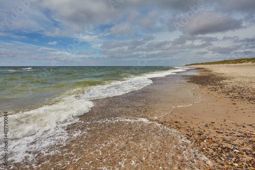 scenic wide angle view of the coastline of the north sea at the beach Nymindegab Strand, Denmark on a sunny summer day with vivie blue sky and clouds