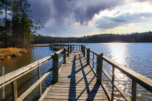 a long gray wooden bridge on the vast blue lake water of Lake McIntosh with stunning skies and lush green and autumn colored trees on the banks of the lake at Lake McIntosh in Peachtree City Georgia photo