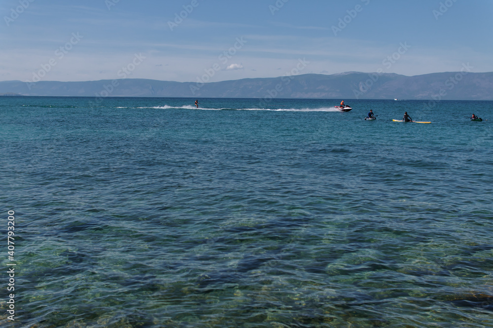 People on sap surfing and man on the water ski on the water of Lake Baikal