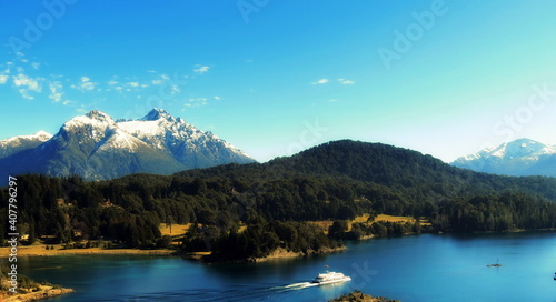Wonderful view of the snowy mountains, lake, forest and blue sky.