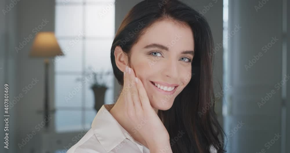 Beauty shot of young woman with perfect face skin after applying moisturizing cream is touching it gently with hand to show how soft and smooth it is. Concept of skincare, cosmetics, healthcare. Beauty shot of young woman with perfect face skin after applying moisturizing cream is touching it gently with hand to show how soft and smooth it is. Concept of skincare, cosmetics, healthcare.