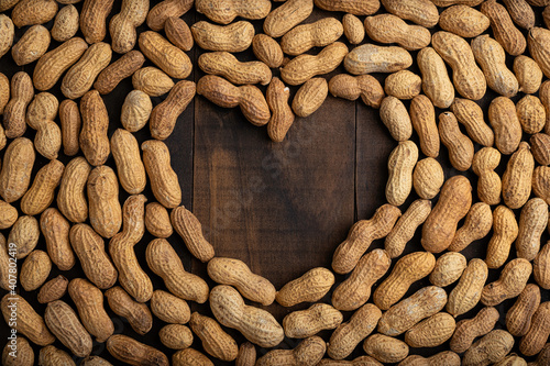 love concept image of heart shape frame made of peanuts on wooden background photo