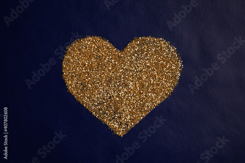 love concept image of heart shape made of golden glitter on blue paper texture background