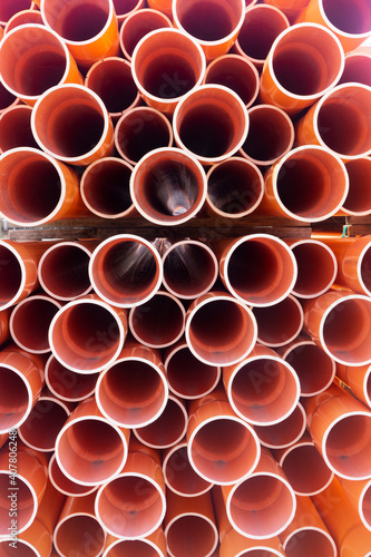 Stacked orange electrical conduit pipes end on.