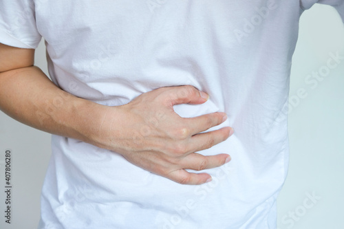 Young man uses his hands to hold his stomach and has a severe stomachache.on isolated white background