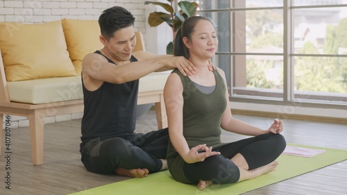 family couple, woman doing YOGA sitting meditating on lotus pose workout at home and the man massage shoulder