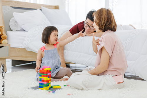 Parent and daughter playing playing a colorful wood block toy in the bedroom at home.leisure activity togetherness.