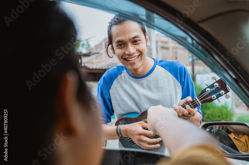 busker smiles when someone rewards from the car on the side of the road