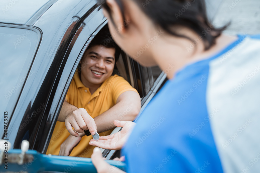 the man smiling from inside the car giving coin by hand from the car window to buskers on the road the man smiling from inside the car giving coin by hand from the car window to buskers on the road