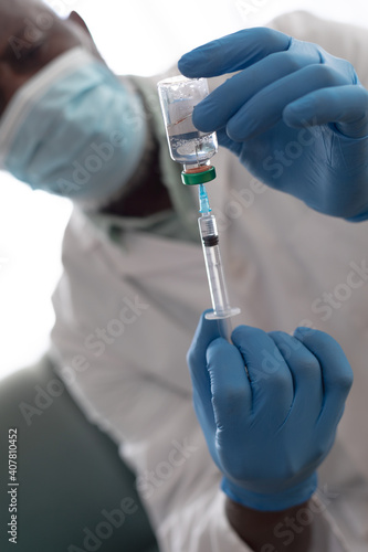 Senior african american male doctor preparing covid 19 vaccination for senior caucasian woman at hom