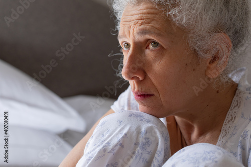 Senior caucasian woman feeling weak sitting on bed photo