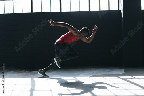 African american man wearing sports clothes sprinting in empty urban building