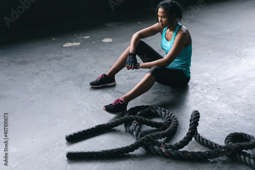 African american woman wearing sports clothes sitting resting after battling ropes in empty urban bu photo