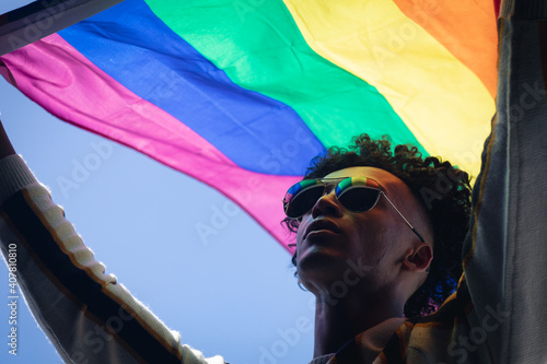 Mixed race man standing on rooftop holding rainbow flag photo