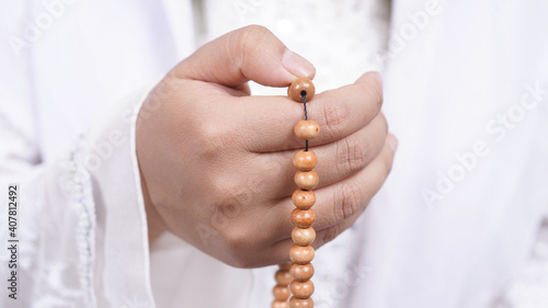 Asian muslim woman wearing prayer beads pray with tasbih in white background
