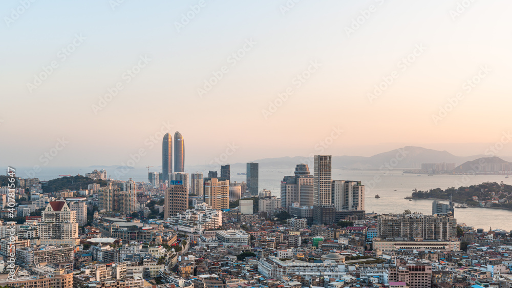 Xiamen city skyline with modern buildings, twin towers, old town and sea at dusk