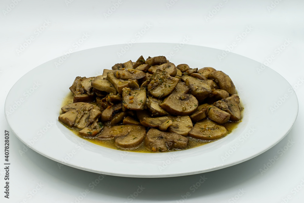 Fried mushrooms, Funghi trifolati, in a white dish isolated on white background