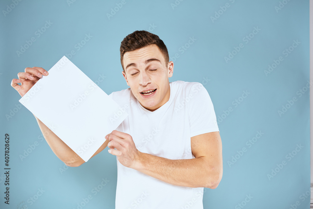a man in a white t-shirt holds a sheet of paper copy space a man in a white t-shirt holds a sheet of paper copy space