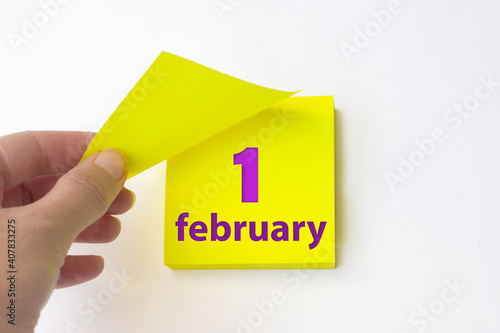 February 1st . Day 1 of month, Calendar date. Hand rips off the yellow sheet of the calendar. Winter month, day of the year concept. photo