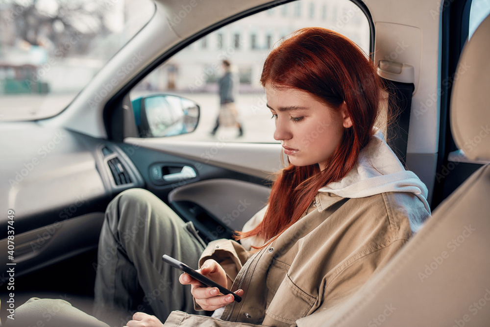Portrait of teenage girl looking tired while using her phone, sitting in the car. Smartphone addiction concept Portrait of teenage girl looking tired while using her phone, sitting in the car. Smartphone addiction concept